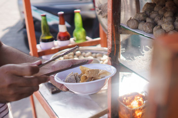 indonesian meatball street food vendor preparing the dish using tongs
