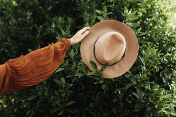 Girl's hand holding a hat with tree behind