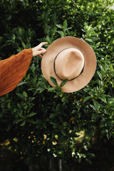 Girl's hand holding a hat with tree behind