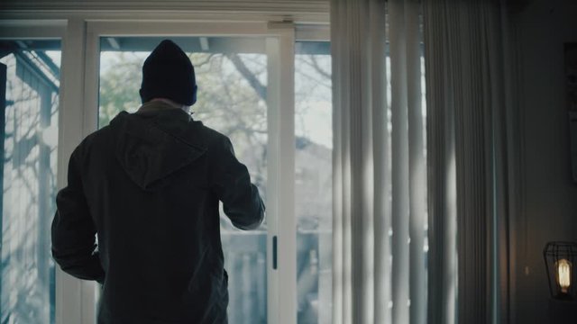 Man looks out his apartment window while sipping a coffee then walks to his desk to start work from home.

Dolly Out Medium to Wide Field of View. 23.976 FPS.