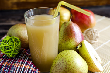 a glass of pear juice and juicy pears on a light background close up