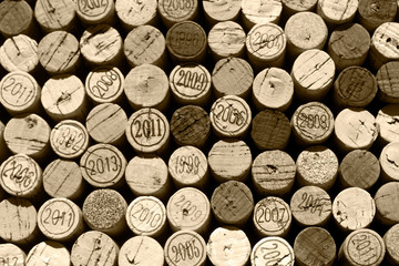 Tops of used natural wine corks, some of them marked with years of vintage, monochrome brown