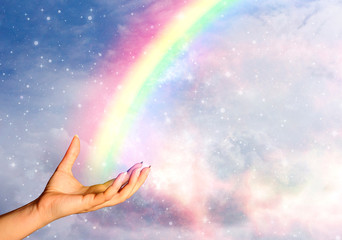 hand with beautiful rainbow over sky with stars and clouds like spiritual and religious, ecological and hope concept , positive thinking 