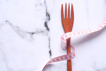 wooden fork and measurement tape on table.