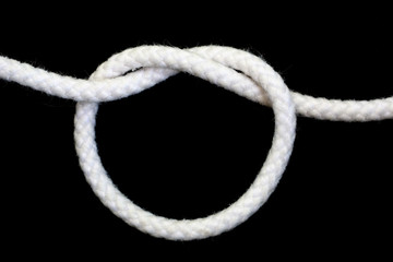 A white rope tied with overhand knot on black background.