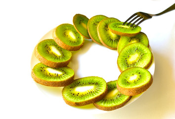 Sliced Kiwi fruit on a white saucer with a fork