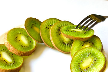 Sliced Kiwi fruit on a white saucer with a fork