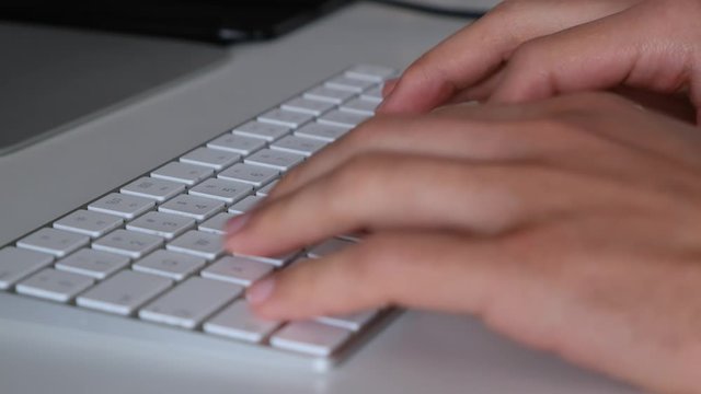Super close up shot of hands typing on a white keyboard. Office worker working from home on a computer with a thin keyboard, bluetooth mouse on modern clean minimalist table, fast key typing, clicking