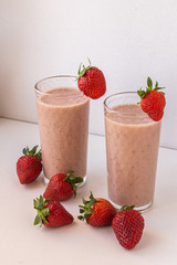 Glasses with strawberry milkshake on a white background with strawberries