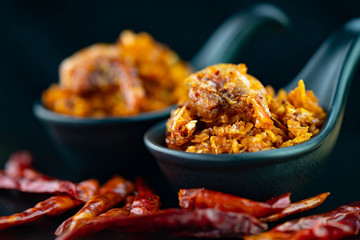 Spicy crispy shrimps chili paste in black spoon on dark background