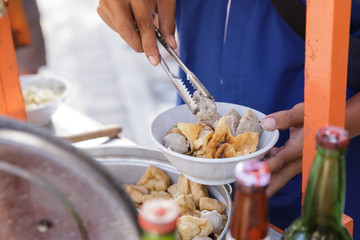 indonesian meatball street food vendor preparing the dish using tongs