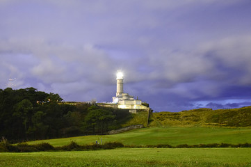 Fototapeta na wymiar lighthouse illuminated at dusk over blue sky