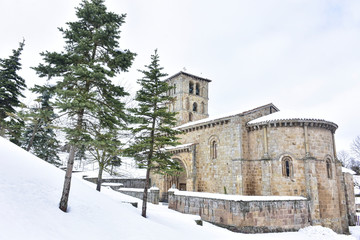 Fototapeta na wymiar Cervatos, Cantabria, Spain; 1-19-2019; views of the church, its bell tower and trees surrounded by snow