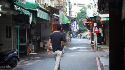 taiwanese guy walking all alone through some alley in taipei, taiwan