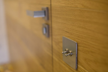 Electric switches on the wooden wall and door handle.