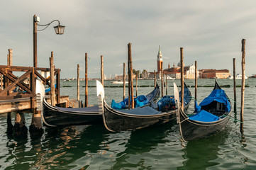 Fototapeta na wymiar Traditional venetian gondolas floating on the water in lagoon on San Giorgio island background