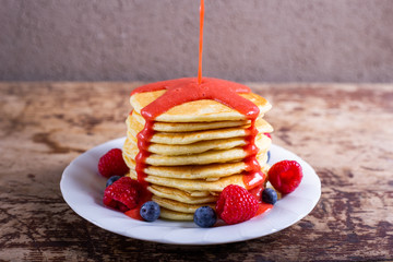 Stack of homemade pancakes with syrup and berries. Typical American breakfast or snack.