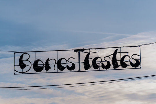 A close-up shot of a decorative sign saying 'Bones Festes' ('Happy holidays' in Catalan) against the background of a cloudy sky in the early morning on a street of a middle-sized Spanish town