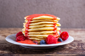 Stack of homemade pancakes with syrup and berries. Typical American breakfast or snack.