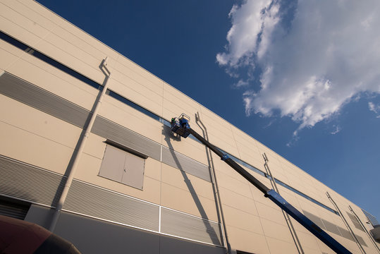 High Elevated Cherry Picker Of Workers On Construction Site