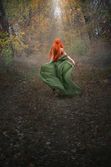 A long-haired red-haired elf girl runs away into the distance through the misty autumn forest. A...