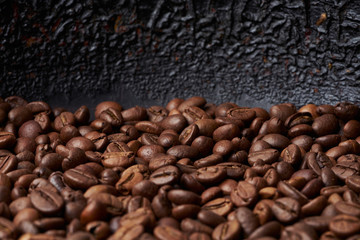 Heap of roasted brown whole coffee beans with dark background