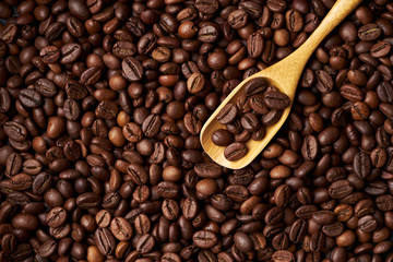 Wooden spoon on a heap of roasted whole coffee beans