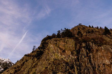 A picturesque landscape view of a mountain cliff peak in the Pyrenees mountain range and the dramatic sky in the Vall de Sorteny (Andorra) natural park on a cold winter evening