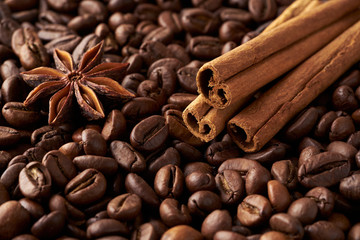 Close-up cinnamon sticks and anise on a heap of roasted whole coffee beans