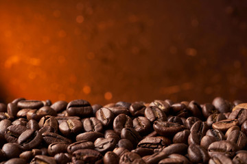 Heap of roasted brown whole coffee beans with a blurry red background