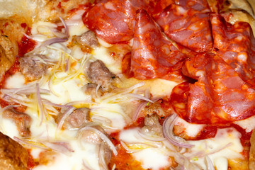 closeup of soft pizza topped with tomato mozzarella salami sausage onion