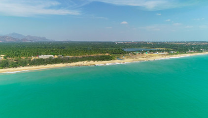 Top view of beautiful white sand beach with turquoise sea water and palm trees, aerial drone shot