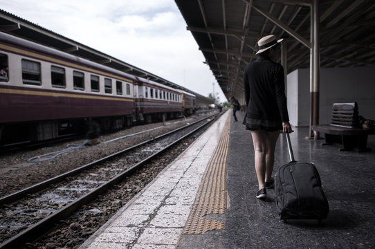 Traveler girl walking and waits train on railway platform.