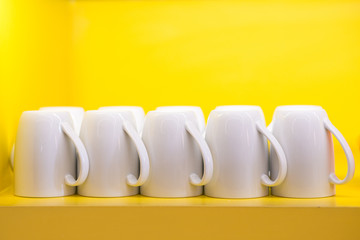 Group of white coffe cup on clear yellow shelf