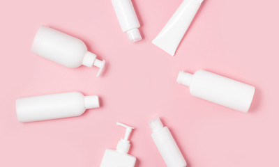 White plastic cans on a pink background. Cosmetics for skin care. Means for washing, disinfecting and washing