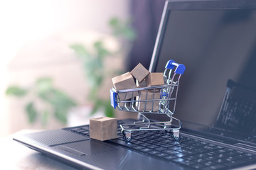 Online shopping with home delivery. Shopping basket and boxes on laptop keyboard.