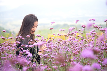 Romantic Asian women are standing to admire the beauty of purple flowers in the mountain gardens at Phetchabun province , Thailand.