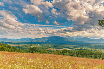 Majestic panorama of a wide mountain valley covered with taiga through which the channal of Siberian river coils