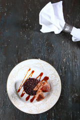 Duck with brown rice on a white plate. The white napkin is secured with a vintage metal ring. Photo on a dark textured background. A copy of this place.