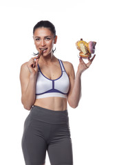 Sexy brunette woman in fitness suit eating candies