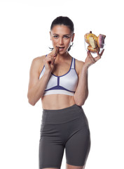 Sexy brunette woman in fitness suit eating candies