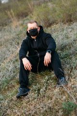 Naklejka na ściany i meble Man in black medical mask on the street. Coronavirus is a virus that is endemic in China.