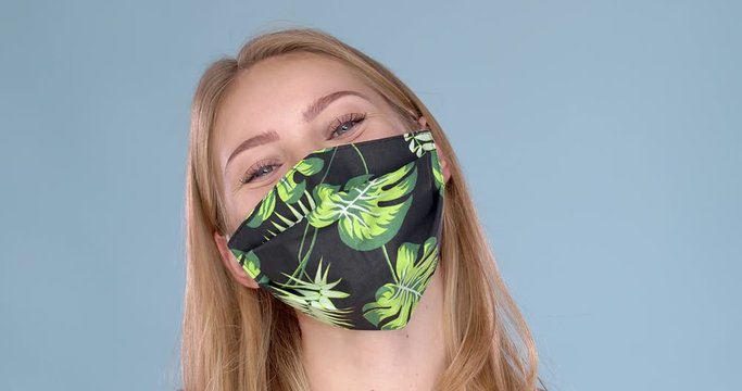 Studio portrait of young woman wearing a face flower patterned mask, looking at camera, close up