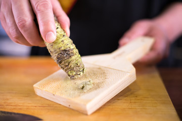 Sushi chef scraping fresh wasabi root prepare for nigiri sushi