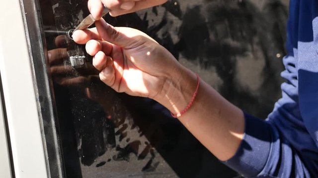 Hands of a man breaking a side window lock of a van - vehicle crime