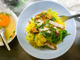 Top view bowl of egg noodles with roast pork, dumpling and vegetable
