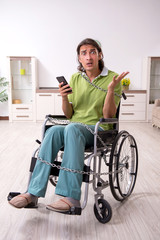 Young male invalid in wheel-chair suffering at home