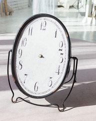 Antique clock with no hands standing on the floor in a white room