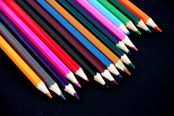 Colored pencils on a black textured background. Suitable for advertising background. Suitable for mockups