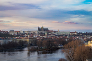 Sunset over Prague Castle. You can see the whole city with pink, yellow, orange and blue colors.